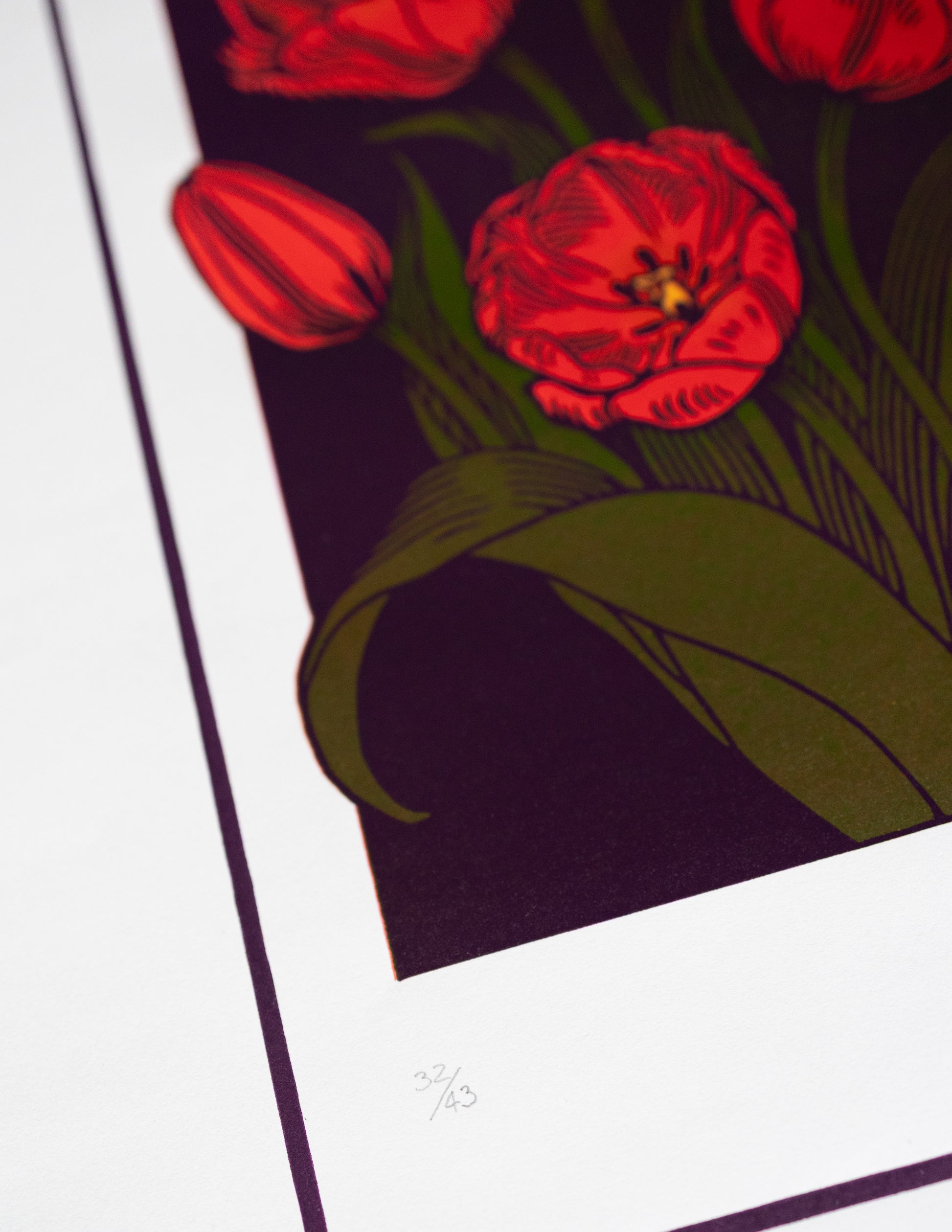 Close-up of a floral design linoprint with red flowers and green leaves on a dark background.