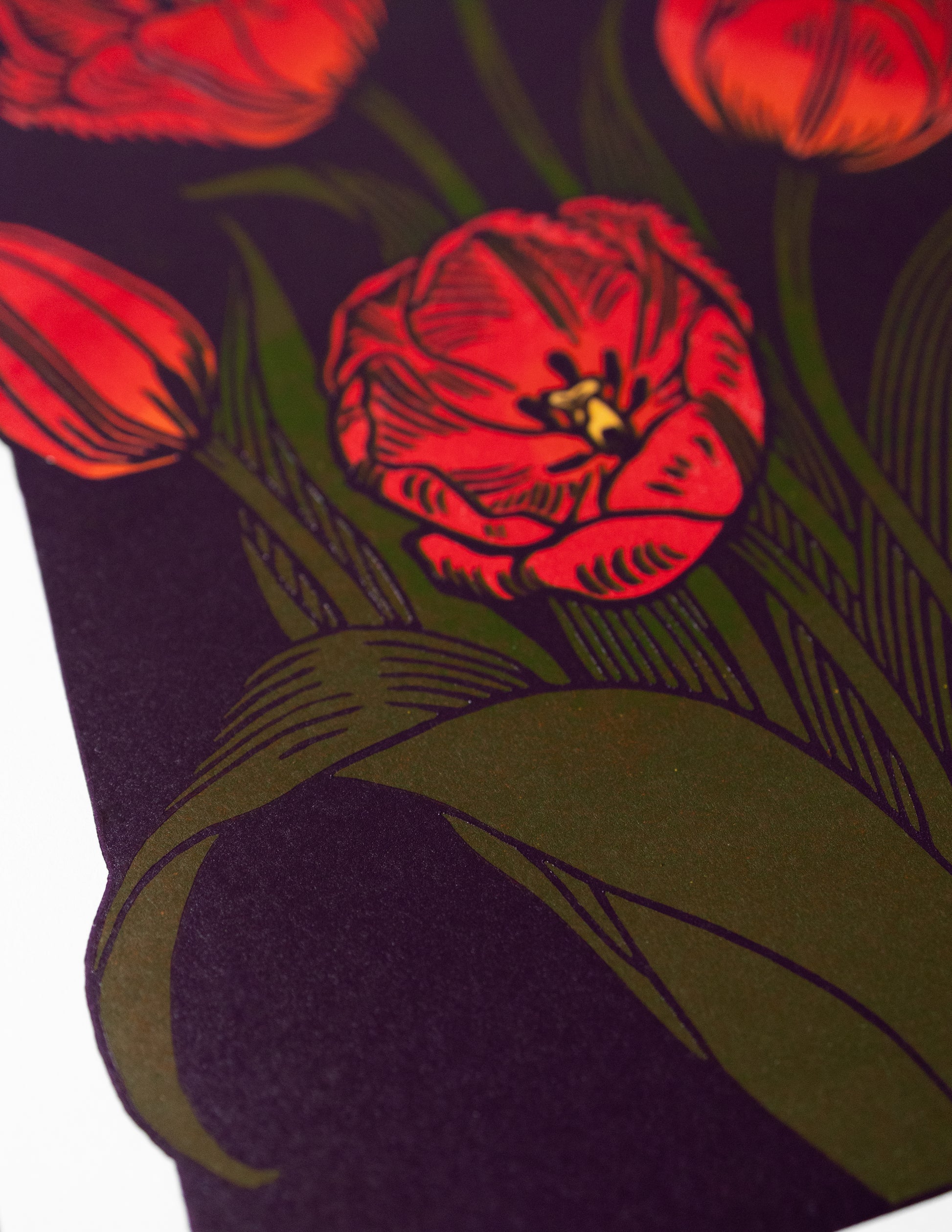 Close-up of a red tulip design linoprint on a dark fabric background